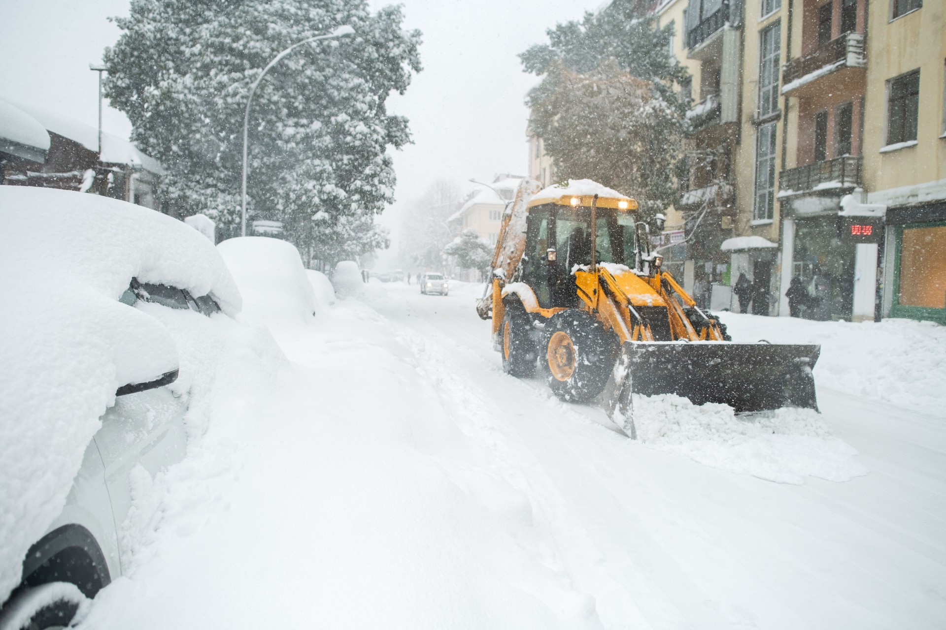 Snowplow cleaning a city street during heavy snowfall